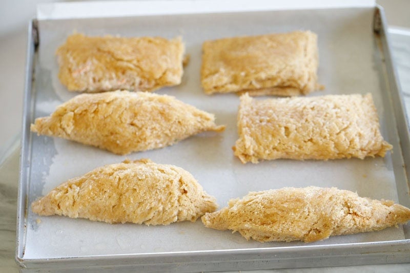 Six pieces of assembled curd rolls on baking tray lined with parchment.