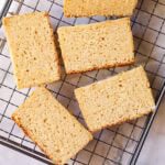Sliced lemon cake on cooling rack.