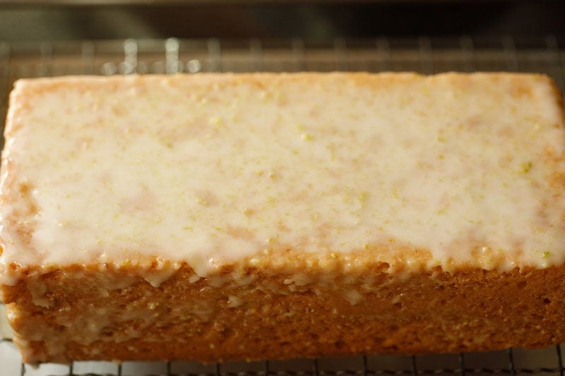 Glazed lemon drizzle cake on rack.