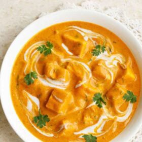 paneer angara gravy in a white bowl garnished with coriander leaves and with text layovers.