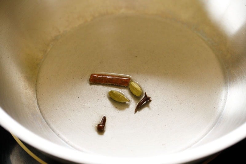 Spices being fried in oil in a skillet.