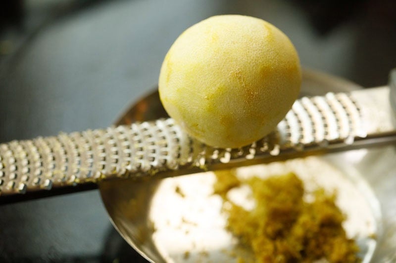 Lemon being zested on a microplane zester.