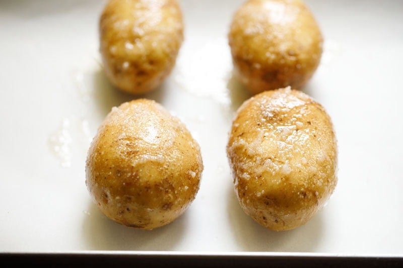 Potatoes on parchment on baking tray.