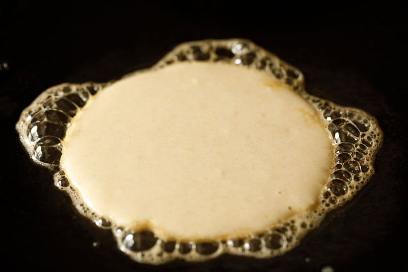 Bubbling buttermilk pancake batter on skillet.