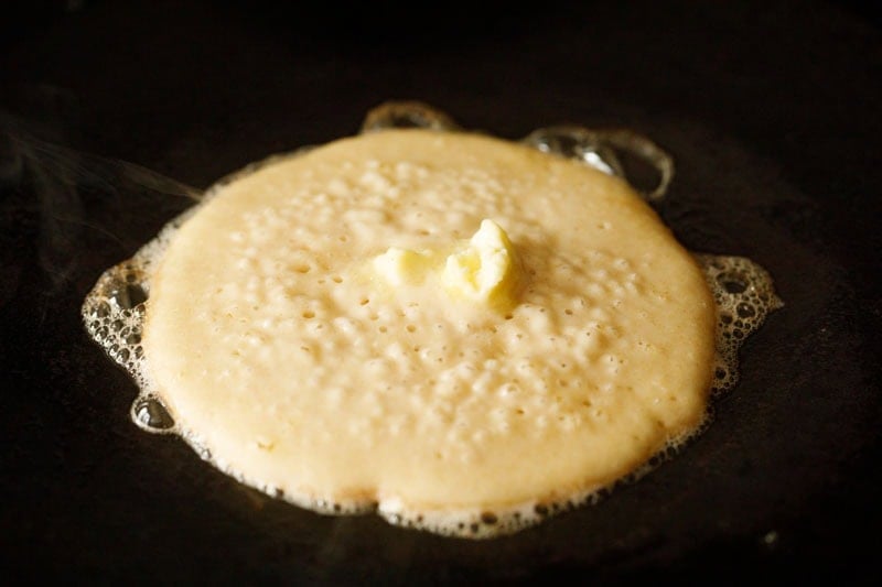 Buttermilk pancake cooking with softened butter on top.