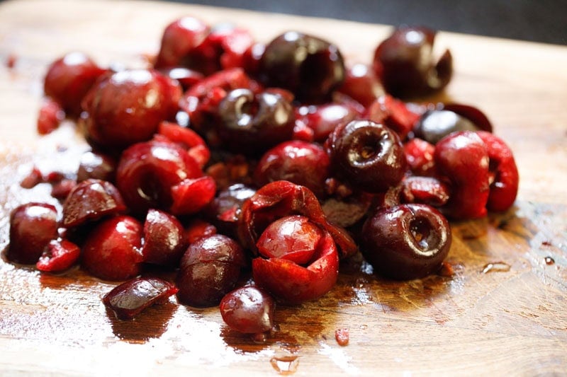 Pitted and chopped cherries on a wooden board.