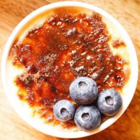 Crème Brûlée with a crisp caramel layer topped with blueberries.