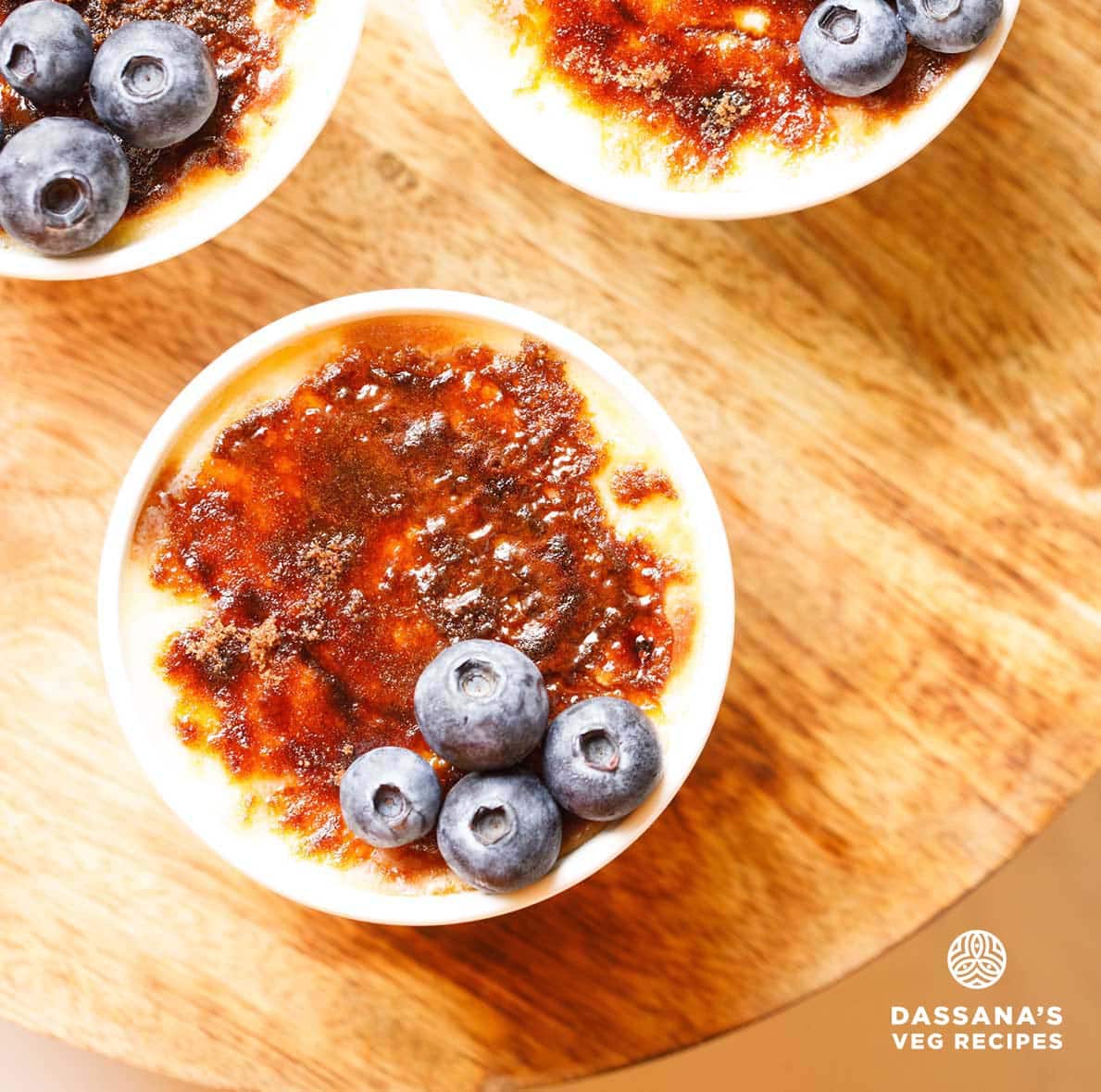 Top view of Creme Brulee with a crisp caramel layer and blueberries on the side.