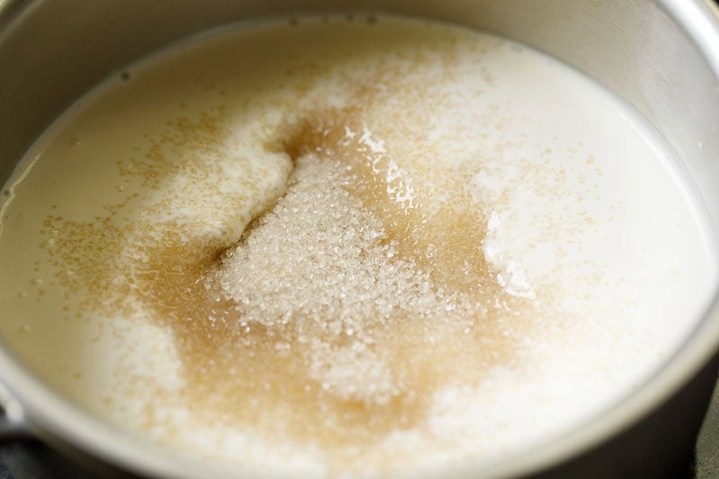 Layer of sugar on cream and milk mixture in saucepan.