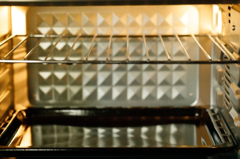 Inside of a preheated and lit oven with rack placed below the broiler or upper heating element.