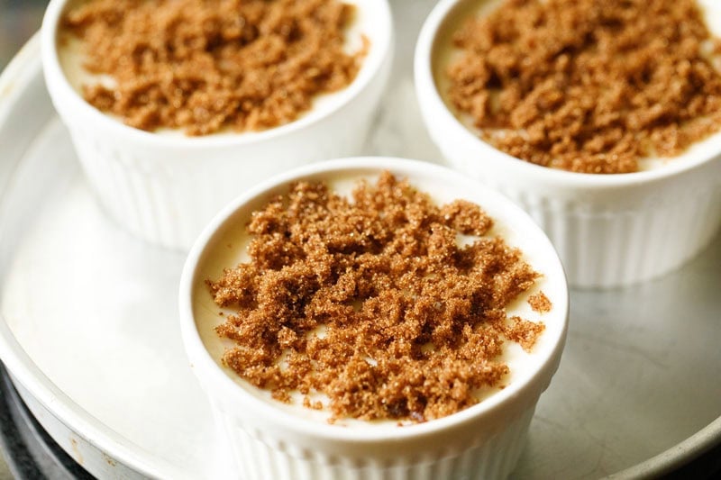 Baked custard in ramekins topped with brown sugar.