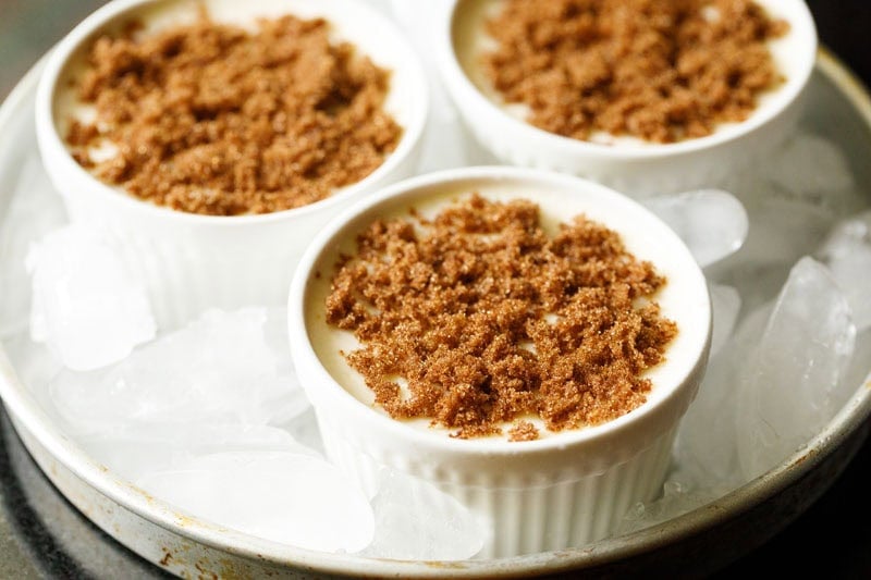 Brown sugar topped custard in baking pan with ice cubes in the pan.