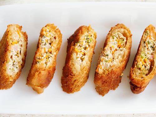 Crispy dahi ke sholay rolls on a white platter.