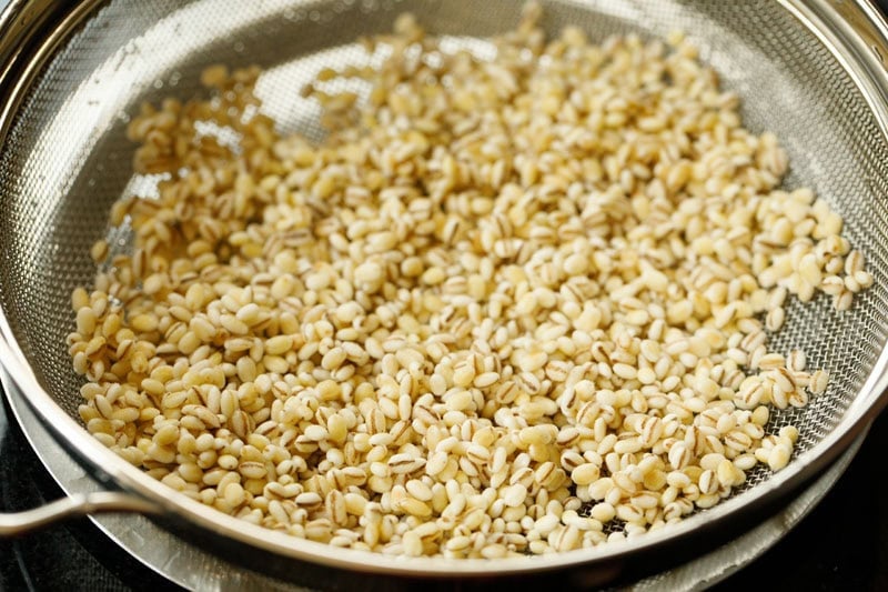 Rinsed pearl barley in mesh strainer.