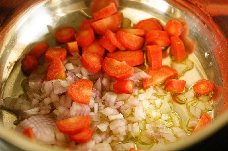 Onions, carrots with olive oil in pan.