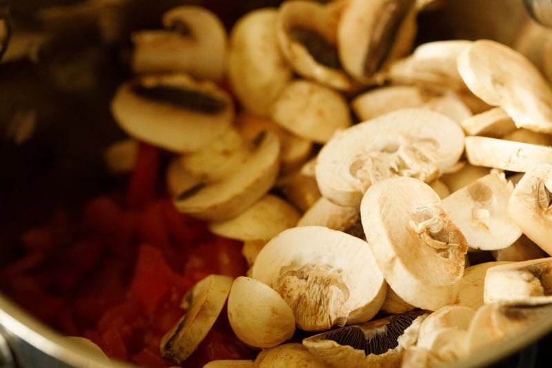 Fresh sliced button mushroom and tomatoes in pan.