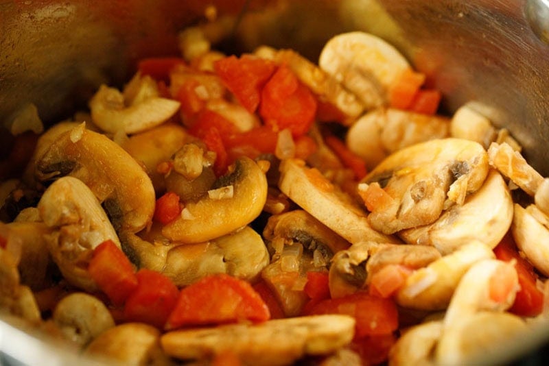 Mushrooms, tomatoes, carrots mixture in pan.