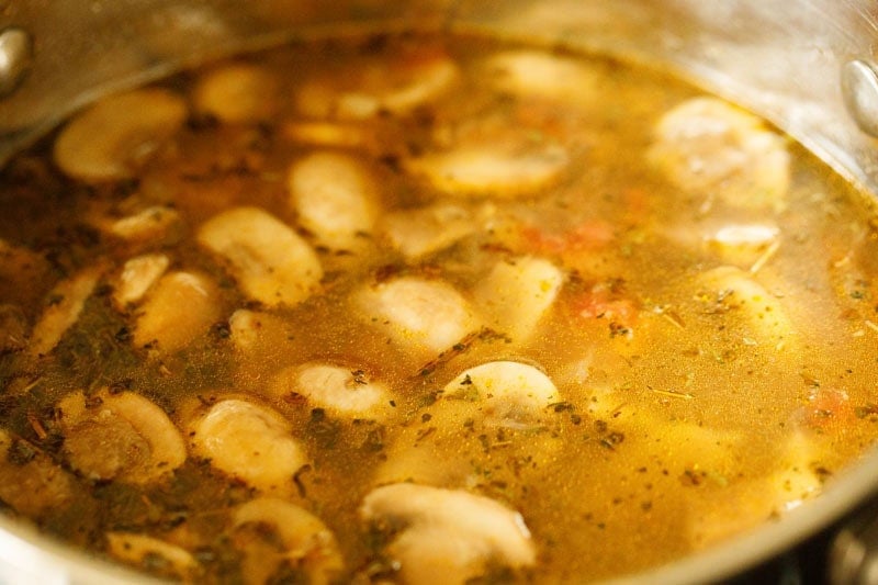 Water mixed with mushrooms, barley etc in pan.