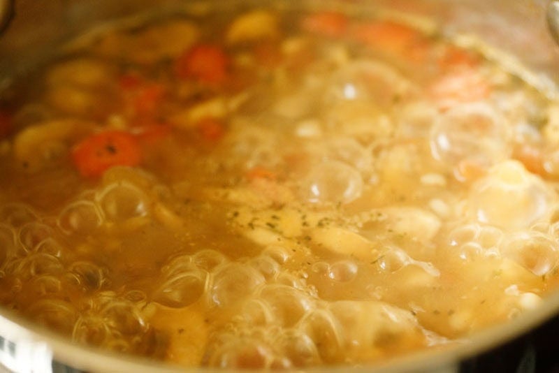 Simmering mushroom barley soup in pan.