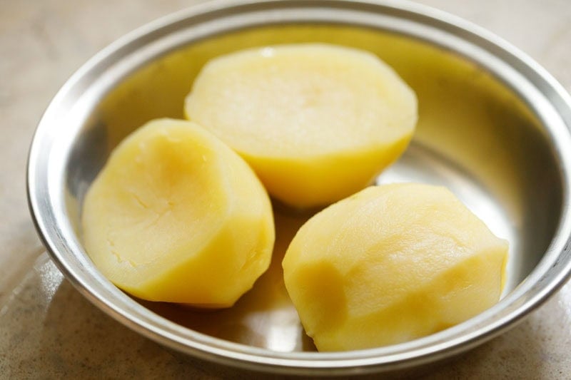 Three peeled potatoes in bowl.