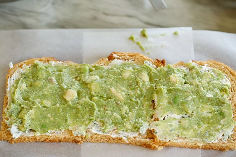 Avocado filling spread on bread slices.