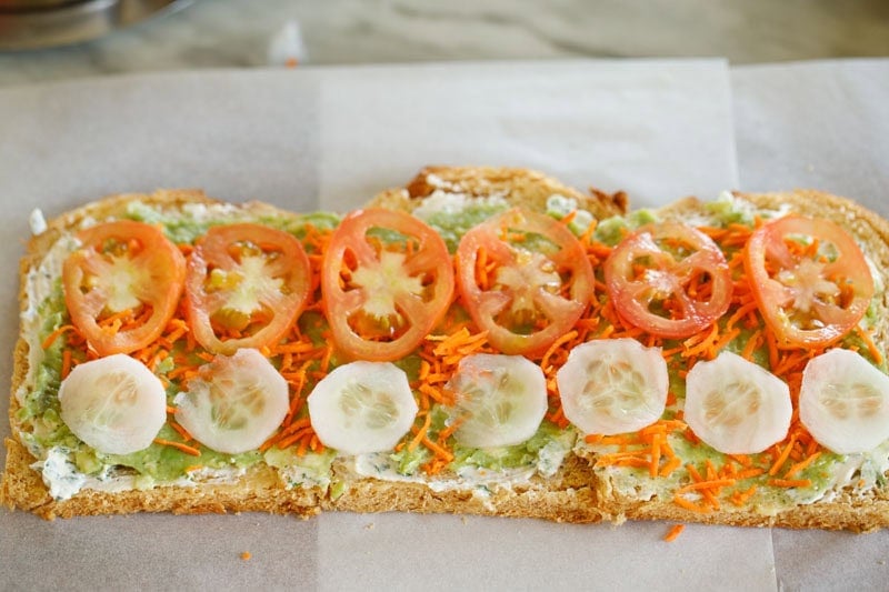 Bread slices topped with grated carrots. sliced tomatoes, and cucumber.