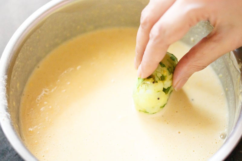 dipping mashed potato balls in prepared batter.
