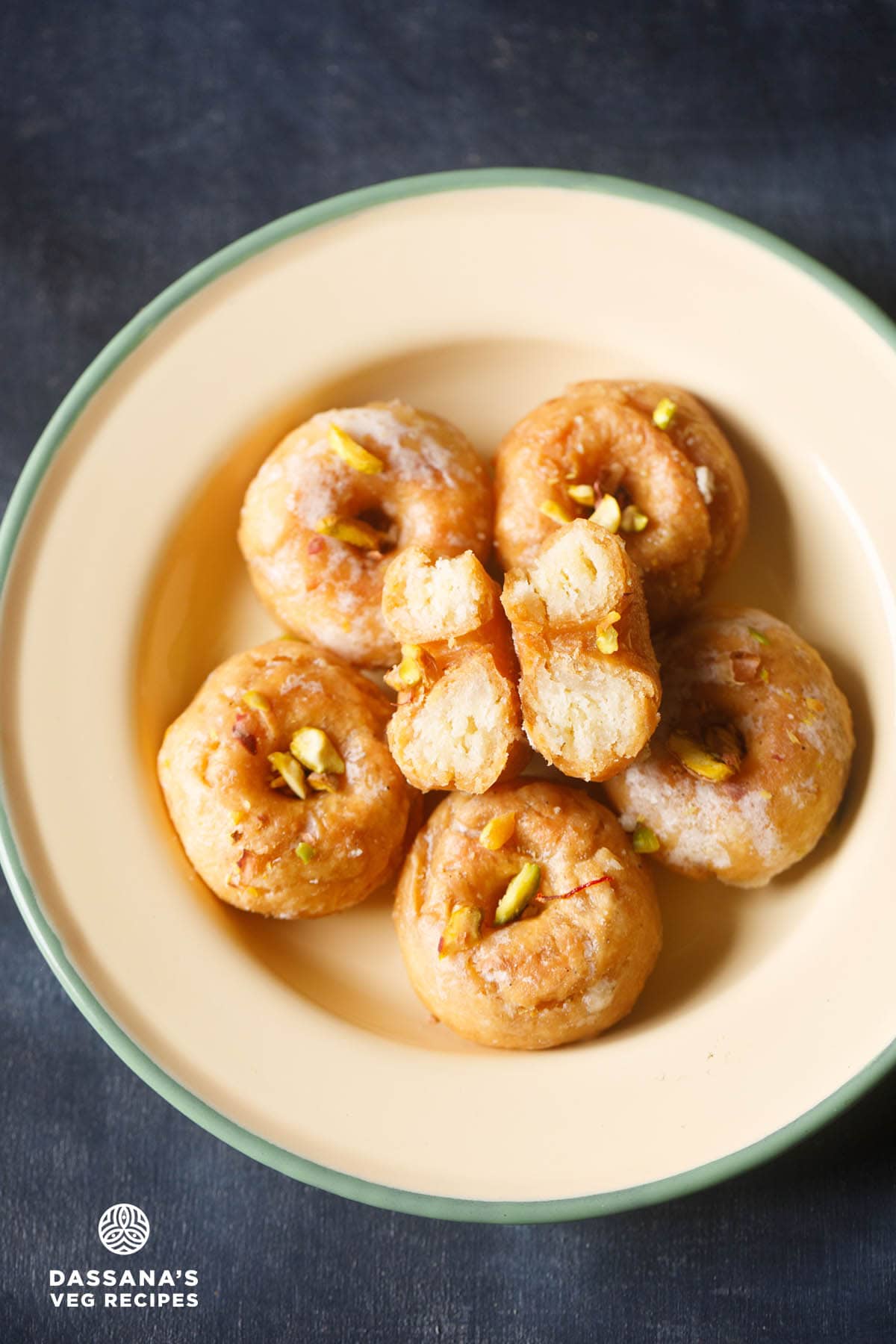badusha garnished with chopped pistachios and served in a ceramic plate.