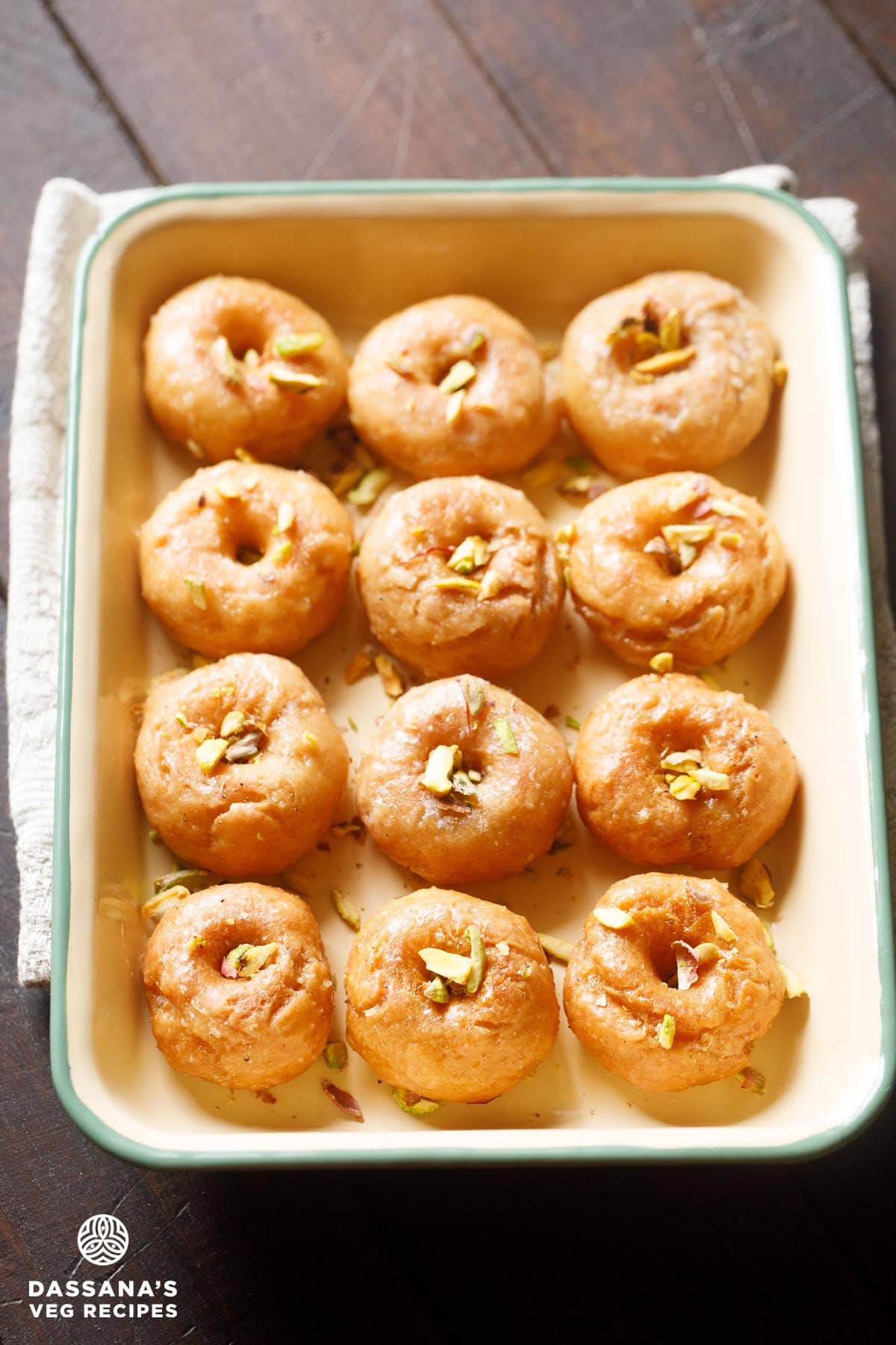 balushahi or badusha garnished with chopped pistachios and served in a ceramic tray.