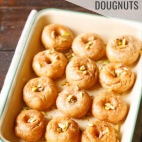 balushahi garnished with chopped pistachios and served in a ceramic tray with text layovers.