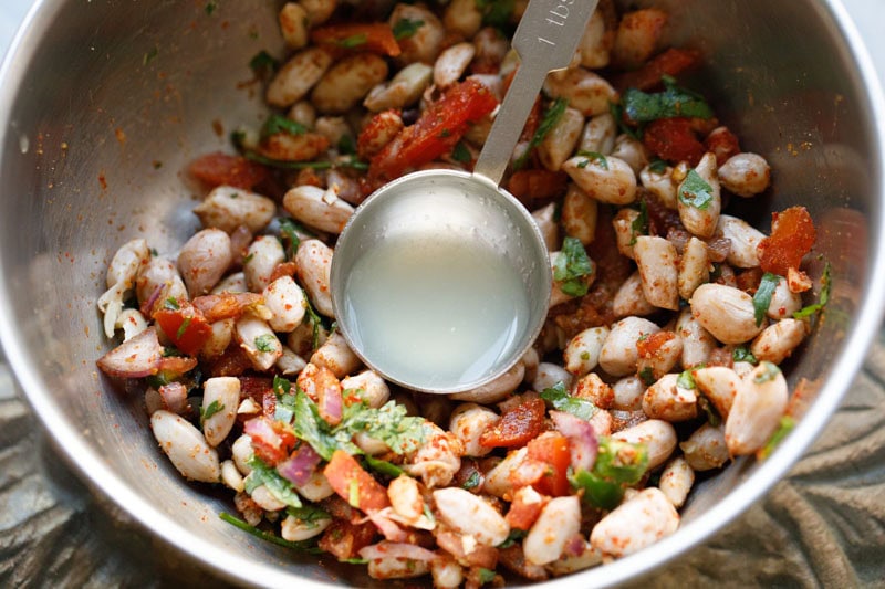 Mixed boiled peanuts with spices, vegetables and a spoon filled with lemon juice.