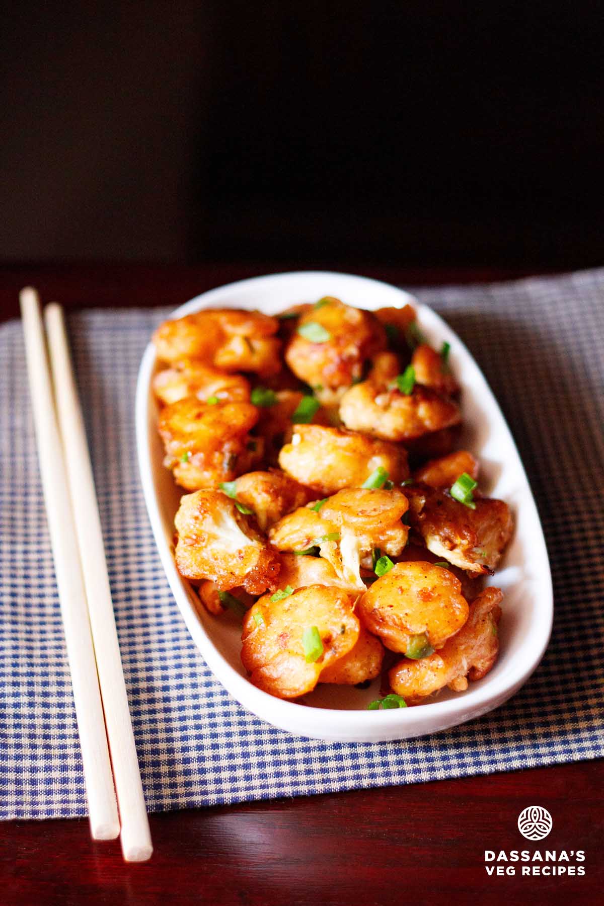 Gobi manchurian in white platter with bamboo chopsticks by side.