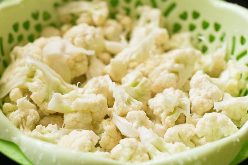 Rinsed cauliflower florets in a green bowl.