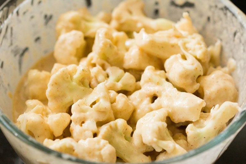 Batter coated cauliflower florets in bowl.