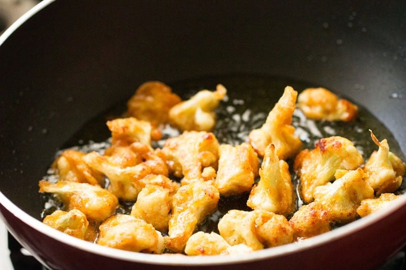 Fried cauliflower pieces in pan.