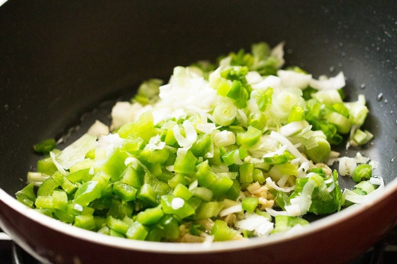 Chopped green onions and capsicum in frying pan.