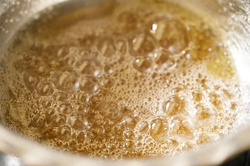 simmering sugar syrup till sticky consistency is achieved in it for balushahi sweet.