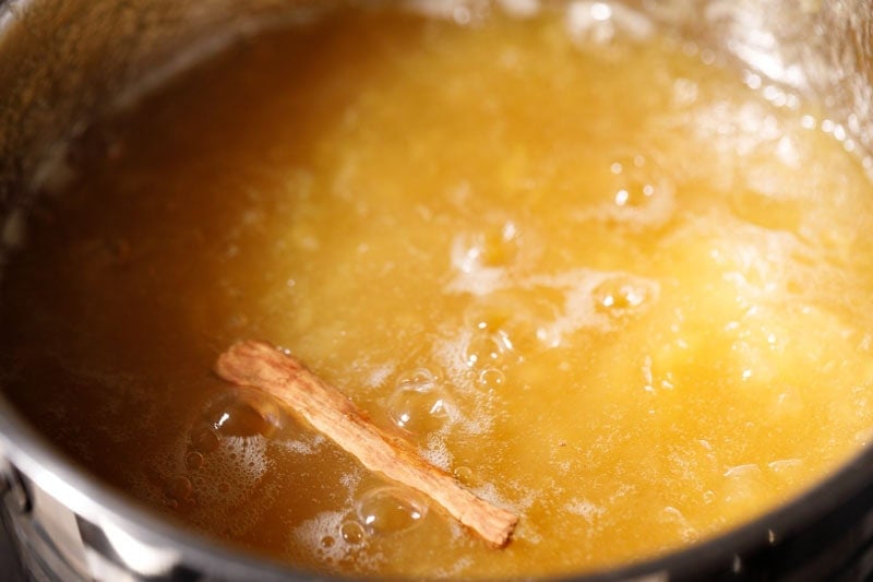 Cinnamon stick on top of apples mixture in pan.