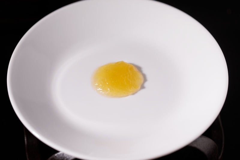 Spoon of apple jam on white plate.