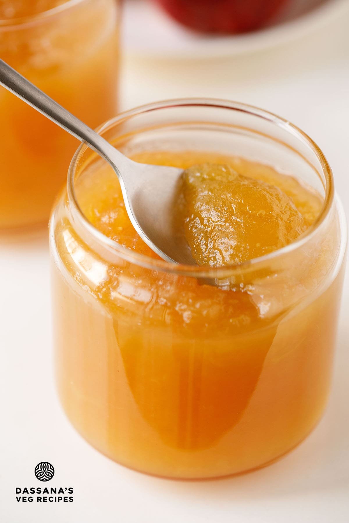 Apple jam on a spoon inside a jar.