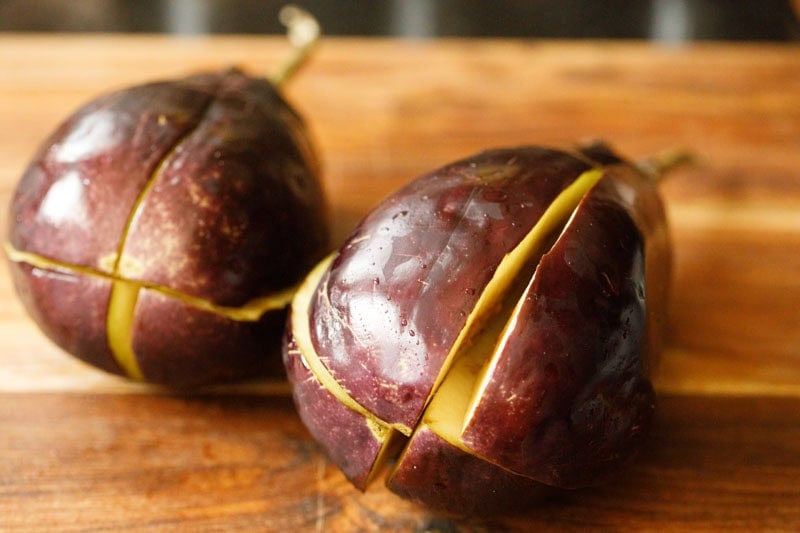 Two sliced eggplants on wooden surface.