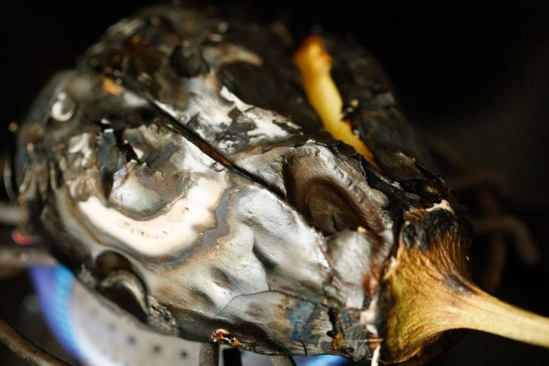 Charred eggplant on a stove.