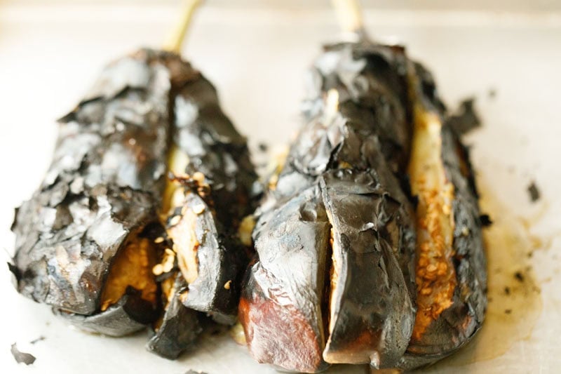 Charred eggplants on a tray.