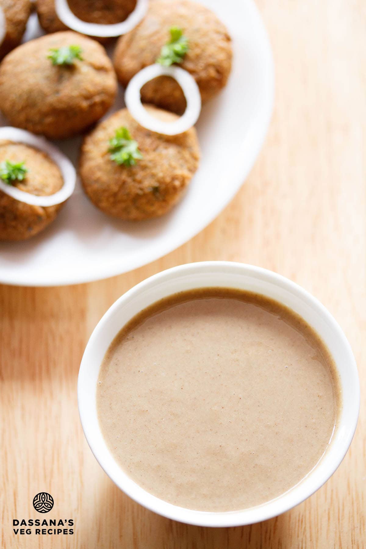 Bowl of tahini with falafel snack in the background.
