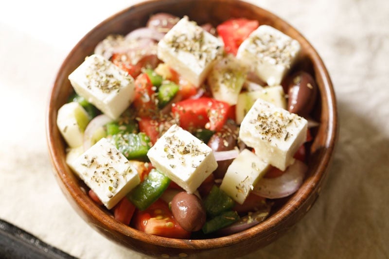 Fresh Greek salad with feta cheese cubes sprinkled with oregano.