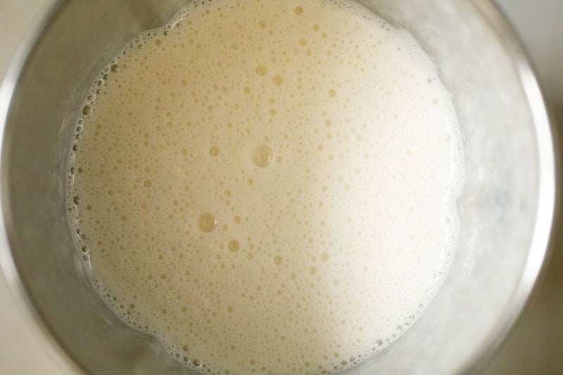 Creamy, frothy banana milk beverage in blender.