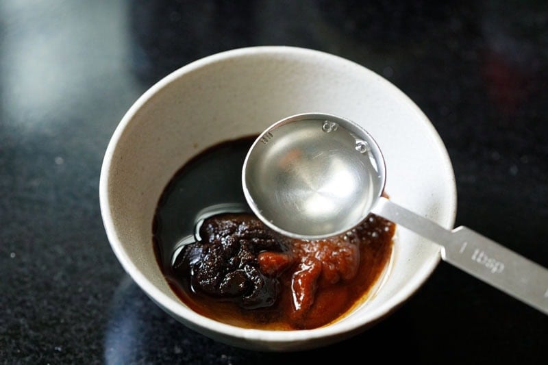 Bowl with sauce ingredients and measuring spoon with cooking sake.