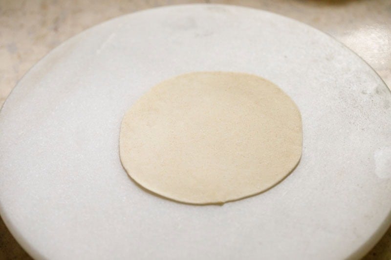 Flat round dough on a rolling board.