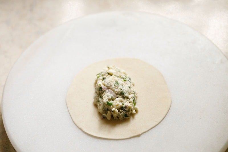 Dough circle with paneer filling on top.