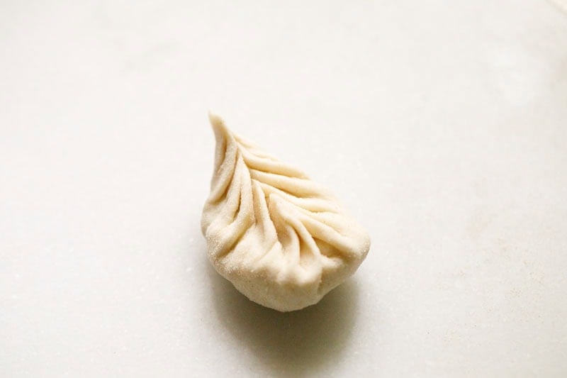Single uncooked paneer momo dumpling.